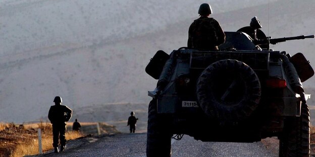 Ein Militärfahrzeug und ein Soldat auf einer Straße, im Hintergrund ein Berg. Ein Militärfahrzeug und ein Soldat auf einer Straße, im Hintergrund ein Berg.