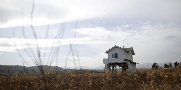 Ein Haus steht mitten in einer zerstörten Landschaft, der Himmel ist grau und bewölkt. Ein Haus steht mitten in einer zerstörten Landschaft, der Himmel ist grau und bewölkt.