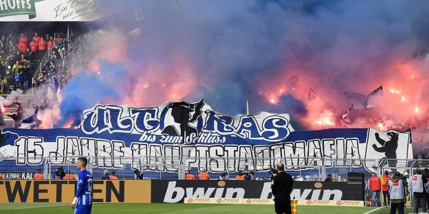 Feuerwerkskörper in dem Fanblock des Hertha BSC brennen und davor auf dem Fußballfeld stehen Spieler Feuerwerkskörper in dem Fanblock des Hertha BSC brennen und davor auf dem Fußballfeld stehen Spieler