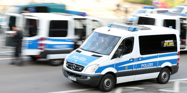 Ein Polizeiauto fährt an mehreren Polizeiautos vorbei Ein Polizeiauto fährt an mehreren Polizeiautos vorbei