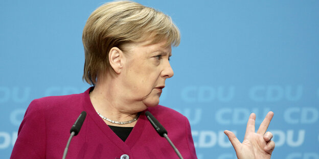Merkel guckt zur Seite und gestikuliert mit der linken Hand Merkel guckt zur Seite und gestikuliert mit der linken Hand