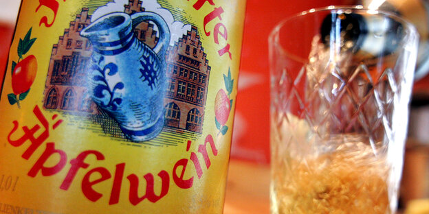 Neben einer Apfelwein-Flasche steht ein leeres Glas Neben einer Apfelwein-Flasche steht ein leeres Glas