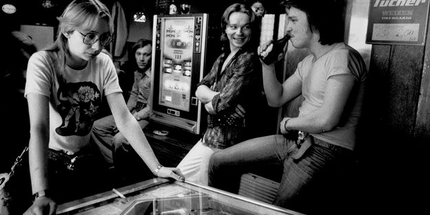Das Foto in schwarzweiß zeigt drei arbeitslose Jugendliche in Berlin-Kreuzberg im Jahr 1982. Sie trinken Bier und spielen Flipper Das Foto in schwarzweiß zeigt drei arbeitslose Jugendliche in Berlin-Kreuzberg im Jahr 1982. Sie trinken Bier und spielen Flipper