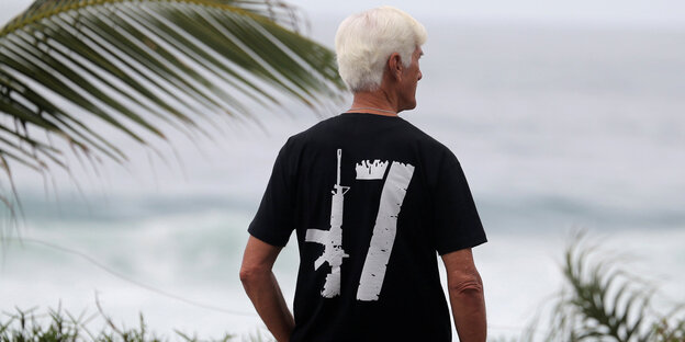 Ein Mann von hinten, auf seinem schwarzen T-Shirt eine AK 47 Ein Mann von hinten, auf seinem schwarzen T-Shirt eine AK 47