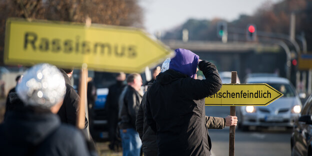 Demonstranten am Rande einer AfD-Veranstaltung zeigen Schilder mit der Aufschrift „Rassismus“ und „Fremdenfeindlich“.