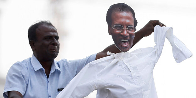 Ein Unterstützer von Sri Lankas Primeminister tanzt mit einer Puppe von Präsident Maithripala Sirisena Ein Unterstützer von Sri Lankas Primeminister tanzt mit einer Puppe von Präsident Maithripala Sirisena