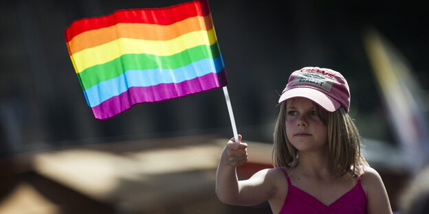 Ein Mädchen schwenkt eine Regenbogen-Flagge Ein Mädchen schwenkt eine Regenbogen-Flagge