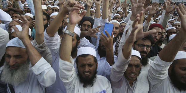 In Pakistan demonstriert eine große Gruppe Männer mit erhobenen Händen In Pakistan demonstriert eine große Gruppe Männer mit erhobenen Händen