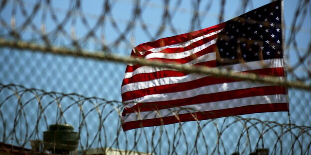 Eine US-Flagge hinter einem Gefängniszaun Eine US-Flagge hinter einem Gefängniszaun