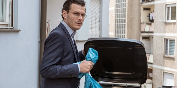 Ein Mann wirft eine blaue tüte in den Müll Ein Mann wirft eine blaue tüte in den Müll