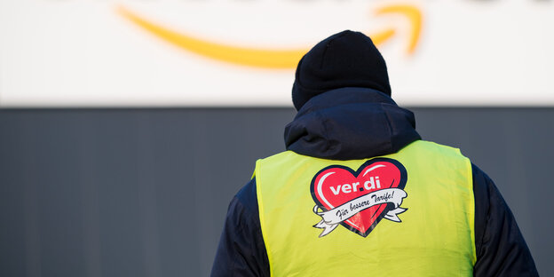 Ein Demonstrant mit Verdi-West vor einem Amazon-Gebäude