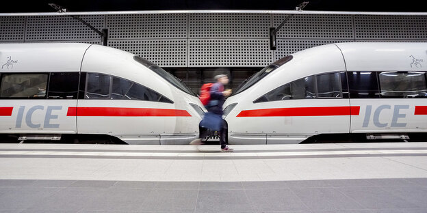 Ein Mann rennt. Hinter ihm sind zwei aneinander gekoppelte ICE-Züge zu sehen Ein Mann rennt. Hinter ihm sind zwei aneinander gekoppelte ICE-Züge zu sehen
