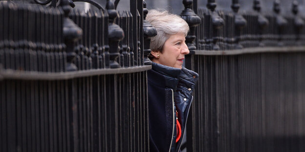 Theresa May tritt zwischen den Gittern eines Zauns hervor Theresa May tritt zwischen den Gittern eines Zauns hervor