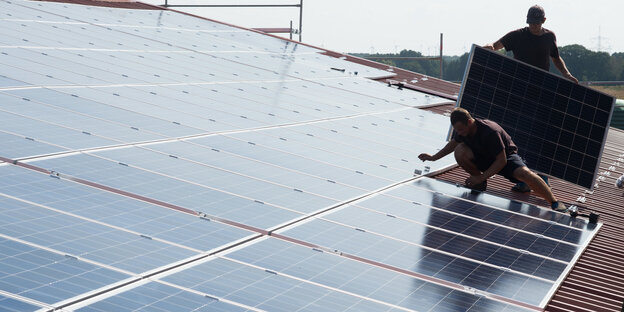 Arbeiter montieren Solarzellen auf einem Dach Arbeiter montieren Solarzellen auf einem Dach
