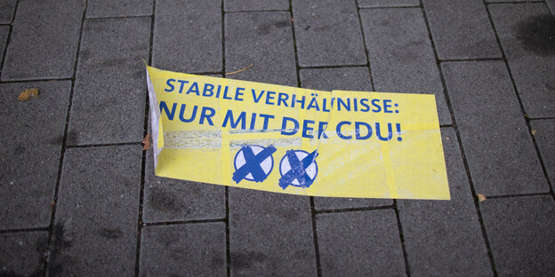 Ein gelbes Transparent liegt auf dem Bürgersteig. Darauf steht: "Stabile Verhältnisse: Nur mit der CDU!" Ein gelbes Transparent liegt auf dem Bürgersteig. Darauf steht: "Stabile Verhältnisse: Nur mit der CDU!"
