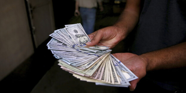 Zwei Hände halten amerikanische Dollarnoten Zwei Hände halten amerikanische Dollarnoten