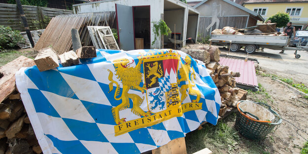 Eine bayerische Fahne, die einen Holzscheit abdeckt vor einer Garage Eine bayerische Fahne, die einen Holzscheit abdeckt vor einer Garage