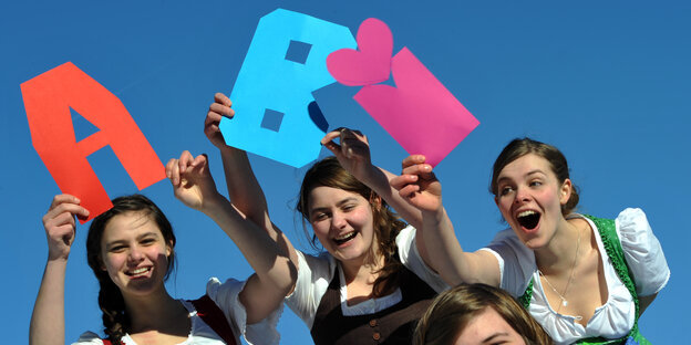 drei Frauen im Dirndl halten die Buchstaben ABI hoch drei Frauen im Dirndl halten die Buchstaben ABI hoch