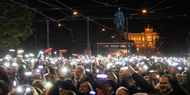 Menschen in der Dunkelheit halten ihre leuchtenden Smartphones hoch Menschen in der Dunkelheit halten ihre leuchtenden Smartphones hoch