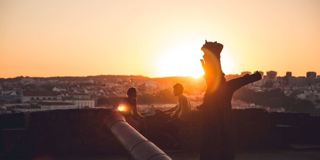 zwei Männer sitzen im goldenen Licht der untergehenden Sonne auf einer Terasse über Lissabon