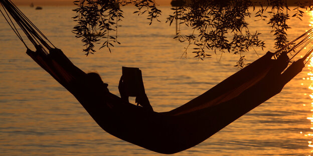Eine Frau liest in einer Hängematte ein Buch Eine Frau liest in einer Hängematte ein Buch