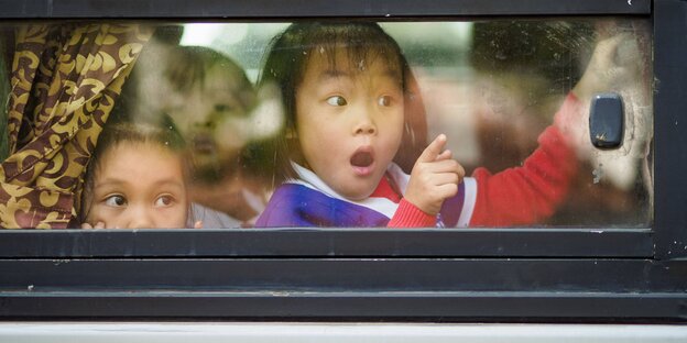 Kinder schauen aus einem Busfenster heraus Kinder schauen aus einem Busfenster heraus