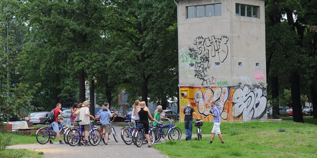 Einige Radfahrer besichtigen einen ehemaligen Wachturm an der ehemaligen deutsch-deutschen Grenze mitten in Berlin Einige Radfahrer besichtigen einen ehemaligen Wachturm an der ehemaligen deutsch-deutschen Grenze mitten in Berlin