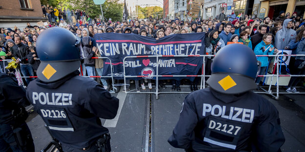 Polizisten stehen vor einer Gruppe von Menschen, die gegen Nazis demonstrieren Polizisten stehen vor einer Gruppe von Menschen, die gegen Nazis demonstrieren