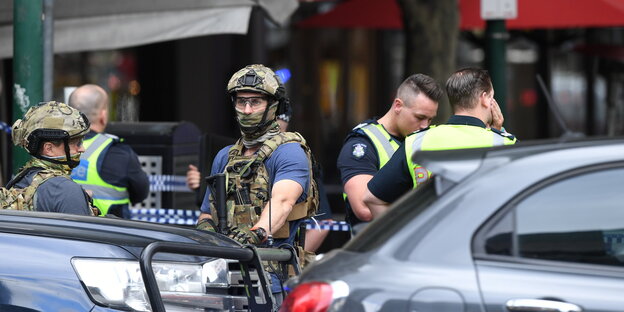 Männer in Uniform stehen in einer Einkaufstraße hinter Autos Männer in Uniform stehen in einer Einkaufstraße hinter Autos