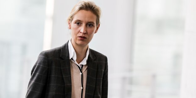 Alice Weidel steht vor einem hellen Hintergrund und schaut ernst Alice Weidel steht vor einem hellen Hintergrund und schaut ernst