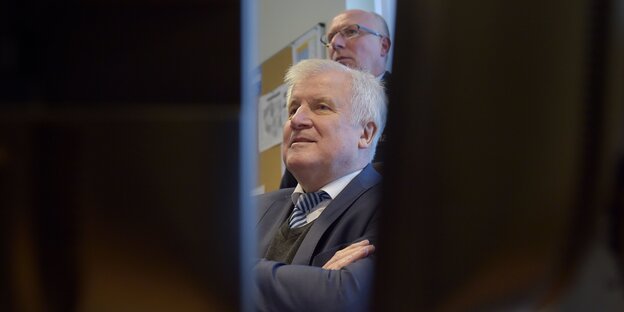 Horst Seehofer, durch einen Spalt zwischen zwei schwarzen Vorhängen zu sehen