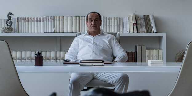 Toni Servillo als Silvio Berlusconi an einem Schreibtisch sitzend Toni Servillo als Silvio Berlusconi an einem Schreibtisch sitzend