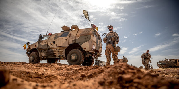 Bundeswehr in Gao, ein Wagen in Tarnfarben, daneben Soldaten Bundeswehr in Gao, ein Wagen in Tarnfarben, daneben Soldaten