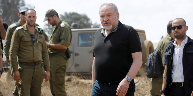 Lieberman unter freiem Himmel, um ihn herum mehrere Männer, einige davon in Uniform Lieberman unter freiem Himmel, um ihn herum mehrere Männer, einige davon in Uniform