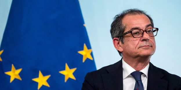 Ein Mann mit Brille sitzt vor einer Europa-Fahne Ein Mann mit Brille sitzt vor einer Europa-Fahne