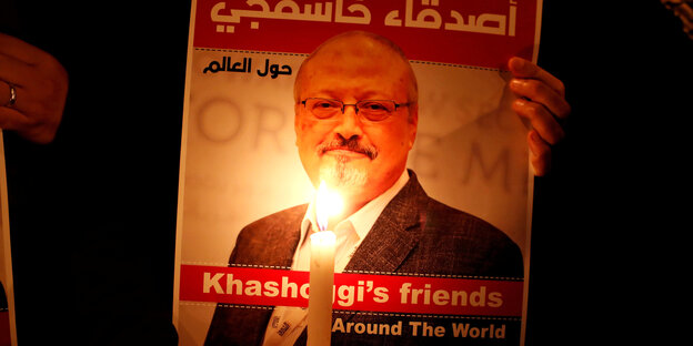 Ein Demonstrant hält vor einem Bild von Khashoggi eine Kerze Ein Demonstrant hält vor einem Bild von Khashoggi eine Kerze