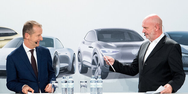 VW-Chef Diess und der Betriebsratsvorsitzende Osterloh bei der Pressekonferenz vor einem Plakat, das vier sportliche VW-Modelle zeigt VW-Chef Diess und der Betriebsratsvorsitzende Osterloh bei der Pressekonferenz vor einem Plakat, das vier sportliche VW-Modelle zeigt