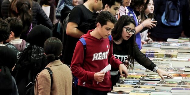sehr viele Menschen drängen sich an an Büchertischen und -regalen sehr viele Menschen drängen sich an an Büchertischen und -regalen