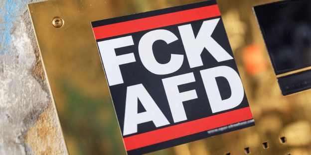 Ein Aufkleber mit der Aufschrift „FCK AFD“ klebt auf einer goldenen Oberfläche Ein Aufkleber mit der Aufschrift „FCK AFD“ klebt auf einer goldenen Oberfläche