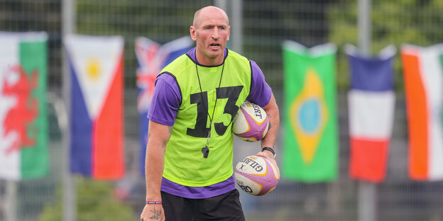 Der Rugbyspieler Gareth Thomas steht mit Trikot und zwei Bällen unter dem Arm auf einem Sportplatz Der Rugbyspieler Gareth Thomas steht mit Trikot und zwei Bällen unter dem Arm auf einem Sportplatz