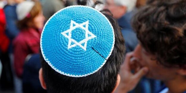 Ein Mann mit blauer Kippa steht in einer Menschenmenge. Ein Mann mit blauer Kippa steht in einer Menschenmenge.