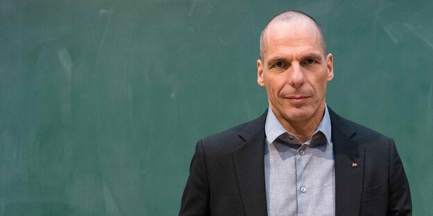 Varoufakis steht vor einer grünen Wand