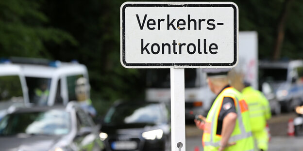 Ein Polizist steht neben einem Schild mit der Aufschrift: "Verkehrskontrolle". Ein Polizist steht neben einem Schild mit der Aufschrift: "Verkehrskontrolle".