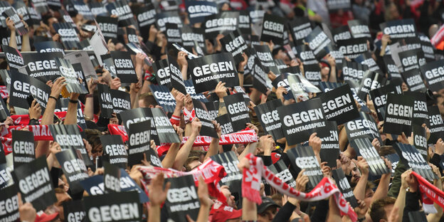 Fußallfans halten Schilder mit der Aufschrift "Gegen Montagsspiele" in die Luft Fußallfans halten Schilder mit der Aufschrift "Gegen Montagsspiele" in die Luft
