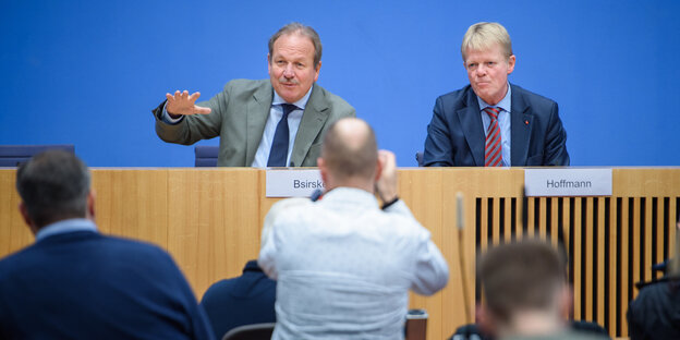 Frank Bsirske und Reiner Hoffmann sitzen nebeneinander hinter einem Tisch,im Vordergrund die Hinteransicht eines stehenden Fotografen Frank Bsirske und Reiner Hoffmann sitzen nebeneinander hinter einem Tisch,im Vordergrund die Hinteransicht eines stehenden Fotografen