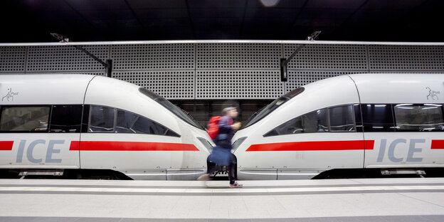 n Mann geht im Berliner Hauptbahnhof an einem ICE entlang.