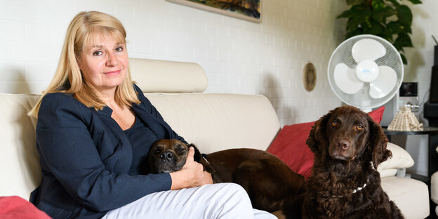 Eine Frau sitzt mit zwei Hunden auf einem Sofa Eine Frau sitzt mit zwei Hunden auf einem Sofa