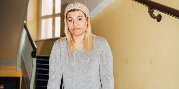 Eine Frau mit blonden Haaren, grauem Pullolver und grauer Mütze Eine Frau mit blonden Haaren, grauem Pullolver und grauer Mütze