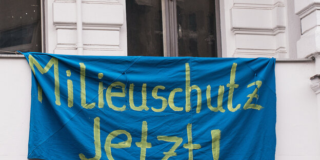 Ein blaues Transparent mit der Aufschrift „Milieuschutz Jetzt!“ hängt unter den Fenstern in einer Gründerzeitfassade Ein blaues Transparent mit der Aufschrift „Milieuschutz Jetzt!“ hängt unter den Fenstern in einer Gründerzeitfassade