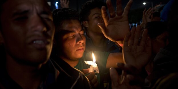 Migranten beten während einer Nachtwache in einer vorübergehenden Unterkunft für mittelamerikanische Migranten in Tijuana Migranten beten während einer Nachtwache in einer vorübergehenden Unterkunft für mittelamerikanische Migranten in Tijuana